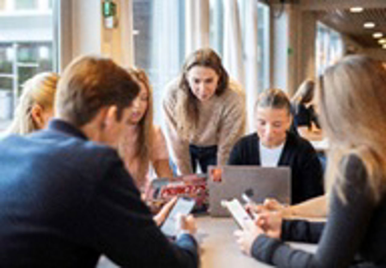 Elever får veiledning av lærer under gruppearbeid